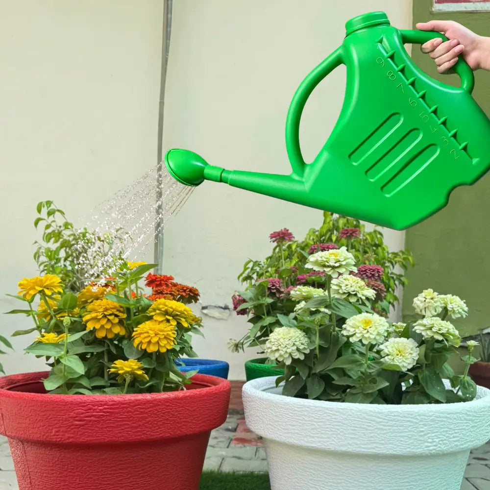 Person watering potted plants with a green watering can.